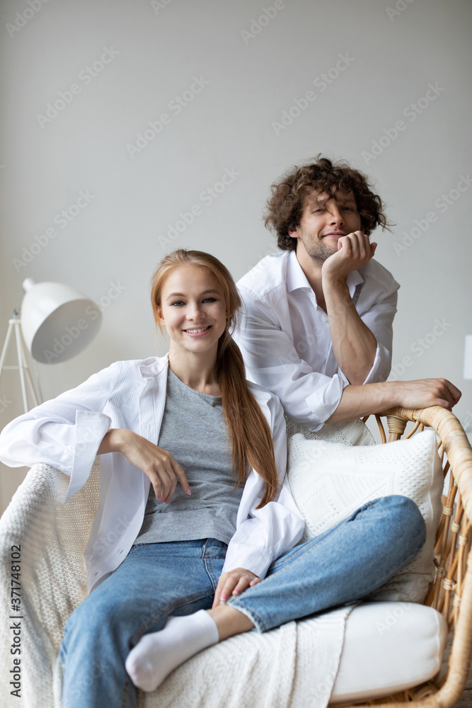 Happy young couple relaxing on cozy chair in living room at home.
