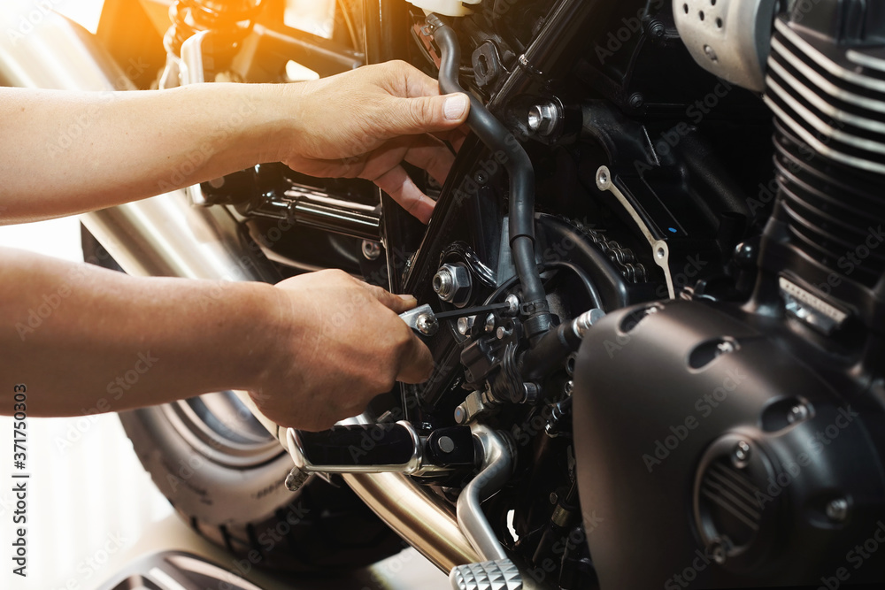 mechanic hold Hex Key Wrench working on motorcycle at motorbike garage , concept of motorcycle maintenance and repair.selective focus