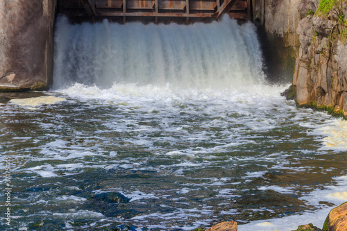 Flowing water with water spray from the open sluice gates of a small dam