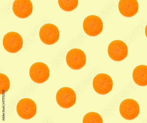 Pattern design with carrot slices on pale yellow background