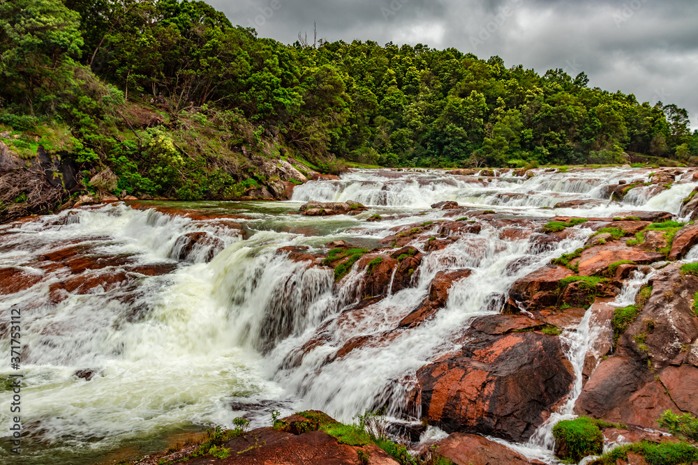 waterfall with red rock and green lush forest flat angle shot waterfall with red rock and green lush forest flat angle shot