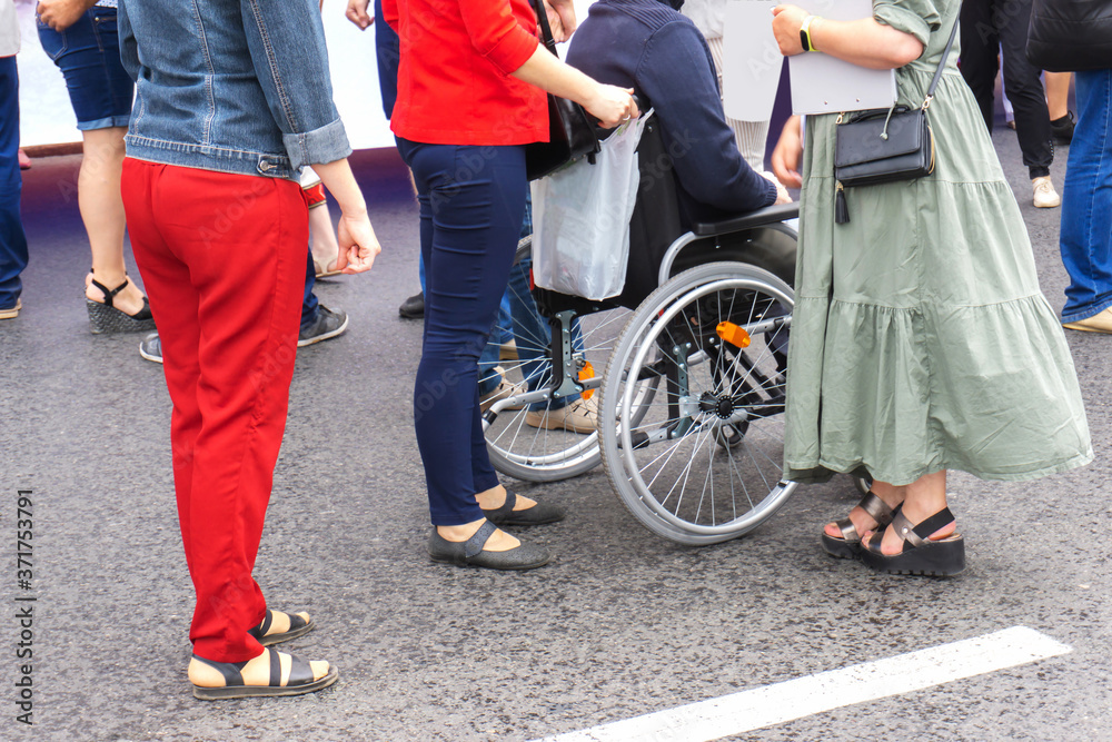 Man with disabilities in a wheelchair on a street in the city. Life of