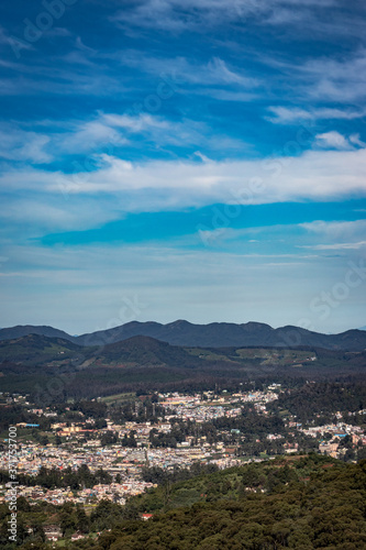 city view with mountain range and bright blue sky from hill top at day © explorewithinfo