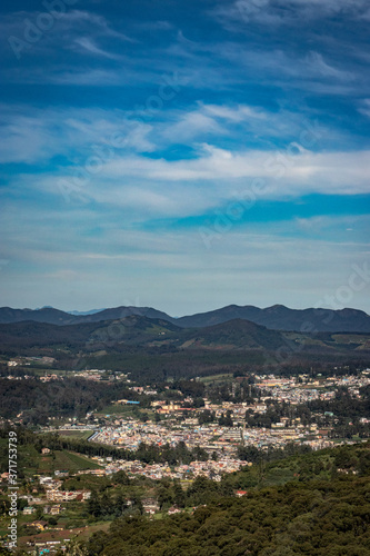 city view with mountain range and bright blue sky from hill top at day © explorewithinfo