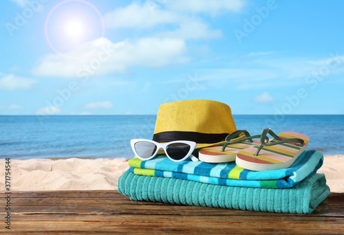 Beach objects on wooden table near sea, space for text. Summer vacation