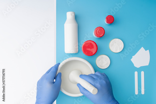 Pharmaceutical lab equipment ,flat or top view on white and blue table and hands working with a mortar.