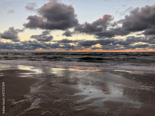Ciemne chmury nad morską plażą po zachodzie słońca. 