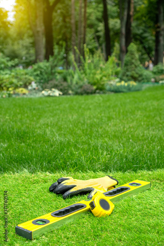 Artificial grass laying background with work tools on a beautiful garden backdrop.