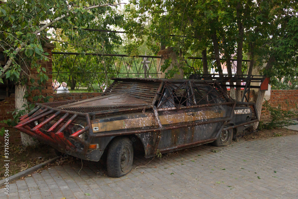 Close-up of a brutal grunge rusty car near a bar in the city of Yarovoe (Altai Territory).