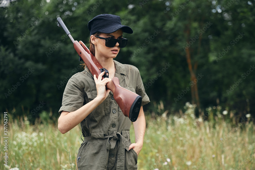 Fototapeta premium Military woman Woman with weapons in dark glasses green jumpsuit fresh air 