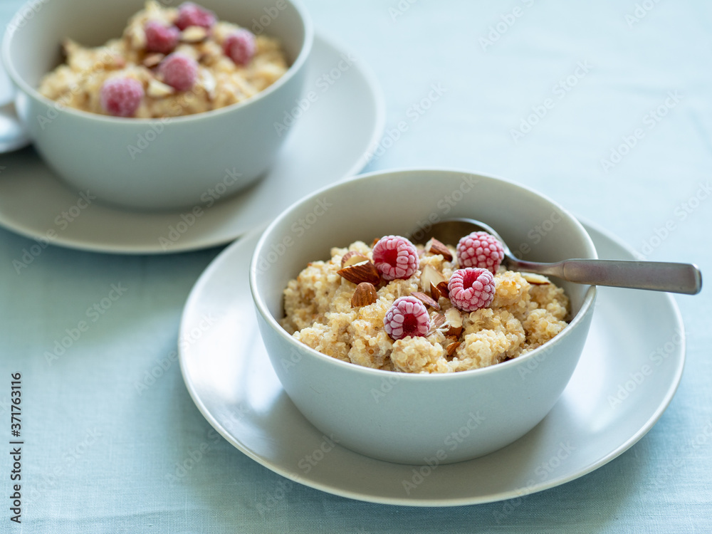 Quinoa porrige on tabletop. Two bowl wit quinoa milk porridge with berries and almond Quinoa porrige on tabletop. Two bowl wit quinoa milk porridge with berries and almond
