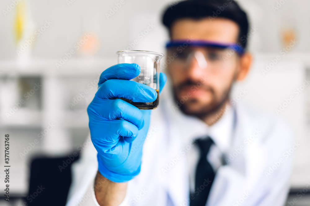 Professional scientist man research and working doing a chemical experiment while making analyzing and mixing liquid in test tube.Young science man looking sample chemical on glass at laboratory Professional scientist man research and working doing a chemical experiment while making analyzing and mixing liquid in test tube.Young science man looking sample chemical on glass at laboratory