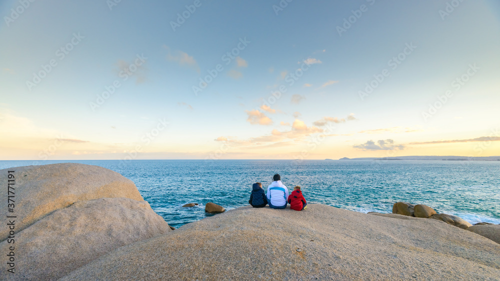 Mother with kids sitting on the edge of the cliff near the ocean in South Australia Mother with kids sitting on the edge of the cliff near the ocean in South Australia