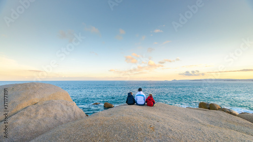 Mother with kids sitting on the edge of the cliff near the ocean in South Australia