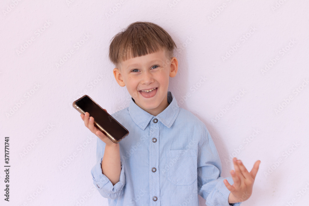 Cheerful boy with a mobile phone in his hand on a light background Cheerful boy with a mobile phone in his hand on a light background