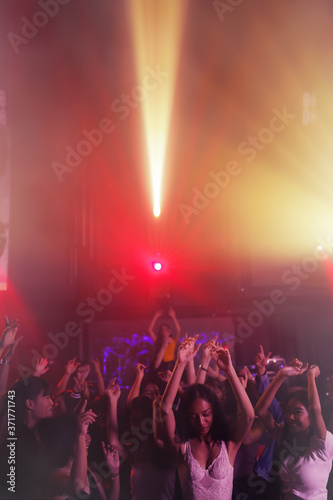 Fotografía crowd of people raises hands dancing together on dancefloor in night club with c