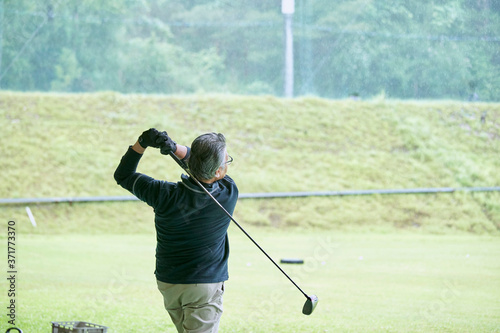 ゴルフ場で練習をするシニアの男性