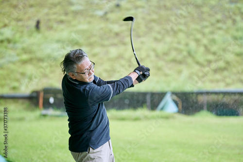 ゴルフ場で練習をするシニアの男性