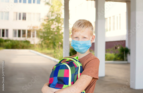 Back to school. School-age boy with a protective medical mask on her on his face with a school backpack. New school year in 2020.C Personal protective equipment. photo