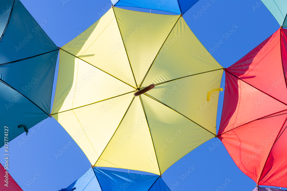 The sky is full of colorful umbrellas. Street with umbrellas in the sky in the village San Bartolome de la torre. Summer decoration and sun protection. Huelva province, Andalusia, Spain The sky is full of colorful umbrellas. Street with umbrellas in the sky in the village San Bartolome de la torre. Summer decoration and sun protection. Huelva province, Andalusia, Spain