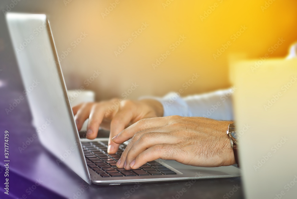 Fototapeta premium Businessman in a blue shirt with a laptop. Hands and keyboard close up.
