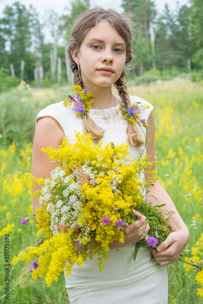In the summertime, a girl is standing on the field and holding a bouquet of yellow wildflowers. In the summertime, a girl is standing on the field and holding a bouquet of yellow wildflowers.
