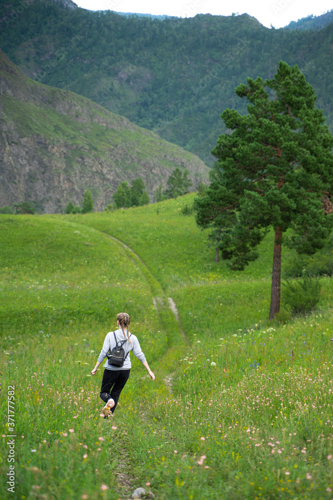Happy young woman runs in a green meadow enjoying freedom. The joy of being in nature. Stress Relief Concept. Summer travel light. Active lifestyle.