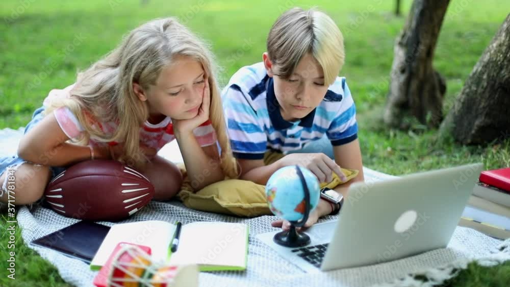Traveling stylish kids learning geography online looking at Earth globe in green park using notebook. 5G internet connect. Boy and girl with notebook device resting on green grass. Laptop gadget. Traveling stylish kids learning geography online looking at Earth globe in green park using notebook. 5G internet connect. Boy and girl with notebook device resting on green grass. Laptop gadget.