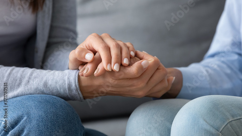 Close up young woman covering hands of mature senior mother, asking for forgiveness, feeling guilty, apologizing indoors. Compassionate grownup daughter comforting supporting retired mum at home.