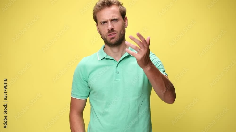 upset young man grimacing, making a hand gesture, arguing and screaming on yellow background upset young man grimacing, making a hand gesture, arguing and screaming on yellow background