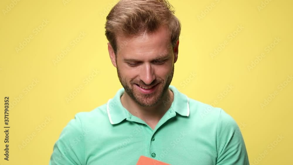 smiling young casual guy admiring, holding up and showing house on yellow background smiling young casual guy admiring, holding up and showing house on yellow background