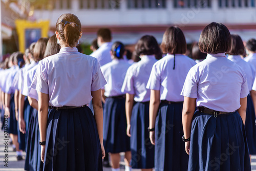 Asian hight school white uniform students stand in line to show respect for their national anthem and pray in the morning.
