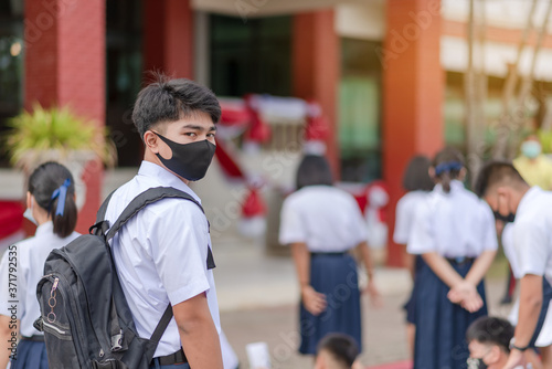 Asian male high school student in white uniform on the semester start wearing masks during the Coronavirus 2019 (Covid-19) epidemic.