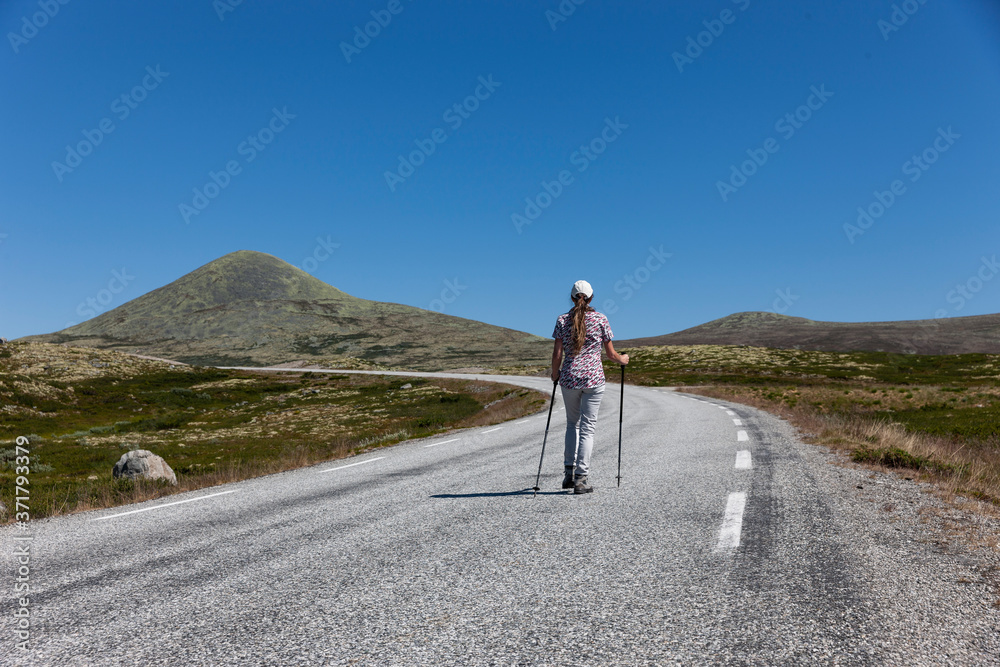 Frau beim Wandern auf einer Landstrasse im Rondane Nationalpark, Norwegen