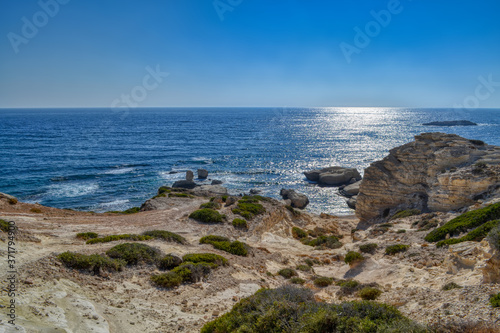 View of the blue water of the Mediterranean Sea and coastal cliffs on the coast of the island of Cyprus. Sunny hot day at the coastline near the town of Paphos.