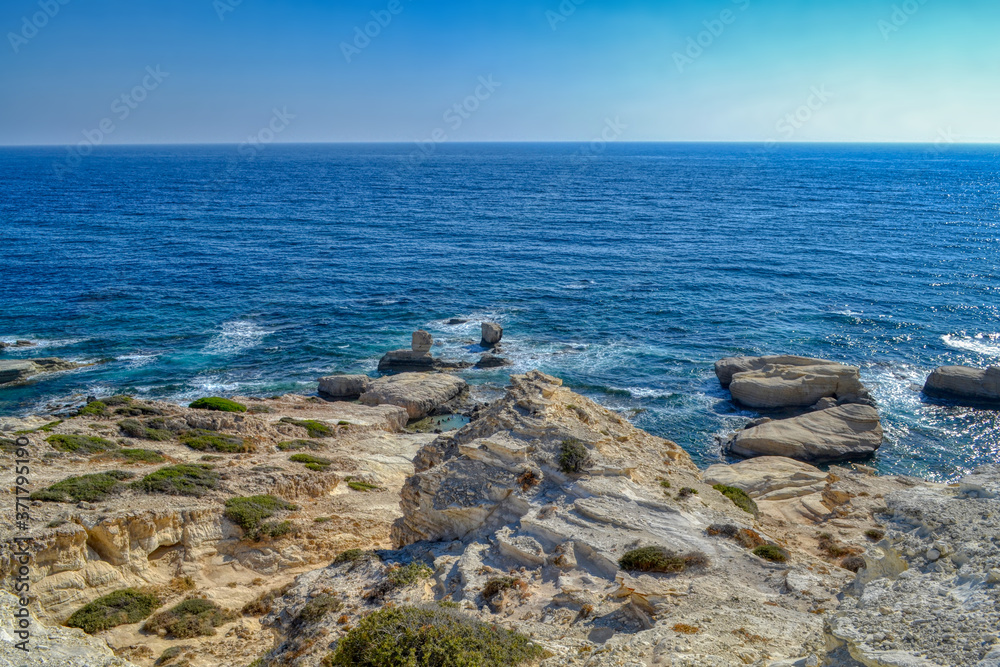 View of the blue water of the Mediterranean Sea and coastal cliffs on the coast of the island of Cyprus. Sunny hot day at the coastline near the town of Paphos.