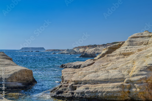 View of the blue water of the Mediterranean Sea and coastal cliffs on the coast of the island of Cyprus. Sunny hot day at the coastline near the town of Paphos.