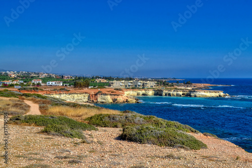 A small lagoon with blue sea water on the coast of Paphos, Cyprus.  In the distance you can see the hotel with the beach.  Waves breaking on coastal cliffs. © Руслан Полуэктов