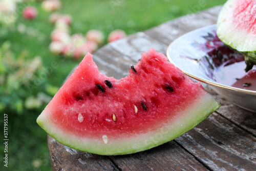Watermelon ripe in a plate on the table in the garden during the day