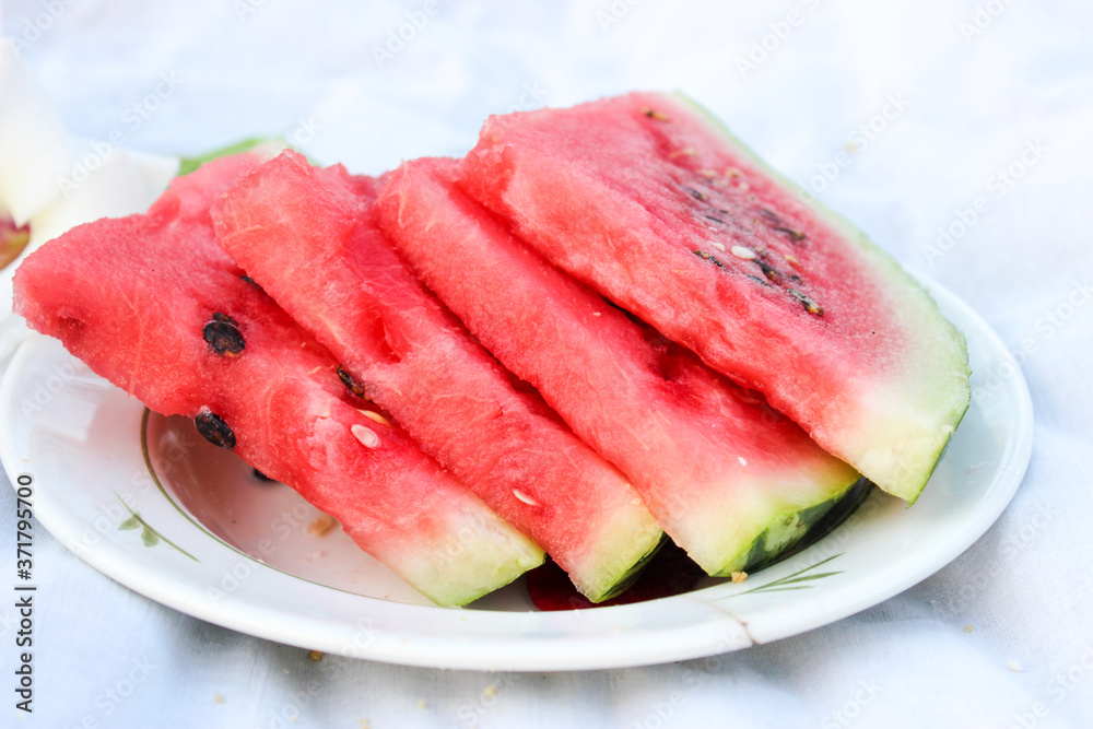 Watermelon ripe in a plate on the table in the garden during the day Watermelon ripe in a plate on the table in the garden during the day