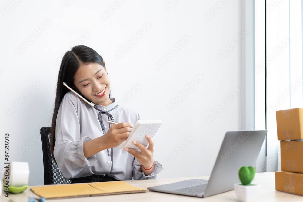 Young Asian woman is selling products online and is confirming an order from a customer. Young Asian woman is selling products online and is confirming an order from a customer.
