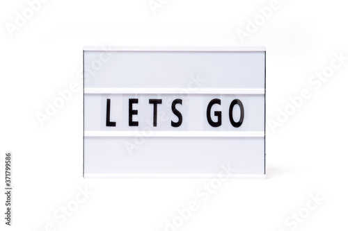 Lets go. Text on a vintage lightbox display placed on a white table on a light background. 