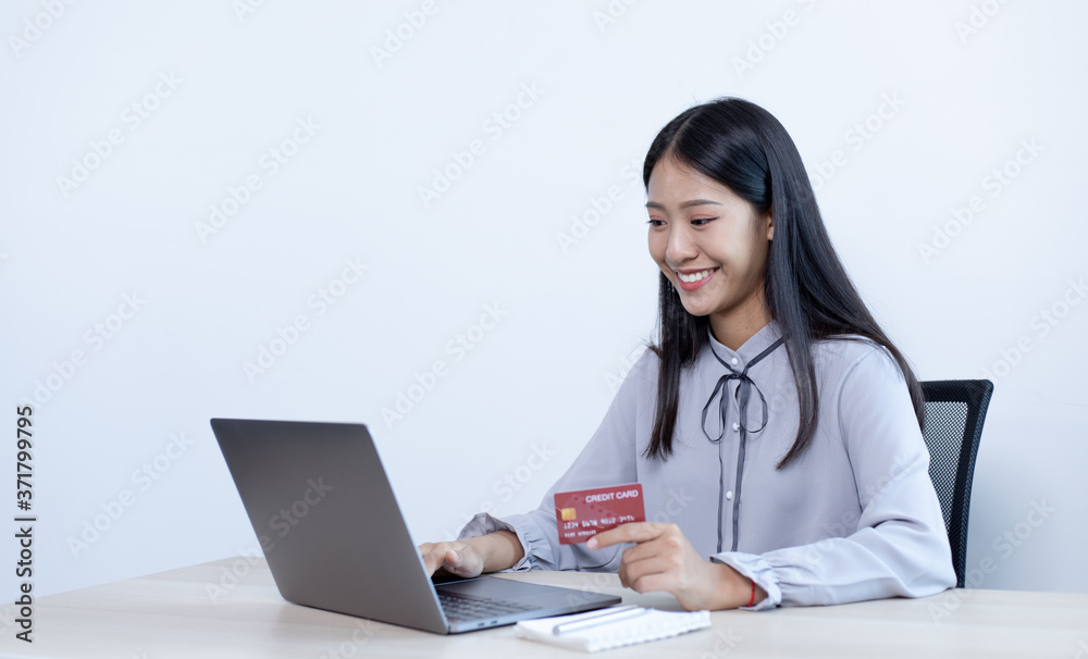 Asian women hold credit cards to shop online on laptops. Asian women hold credit cards to shop online on laptops.