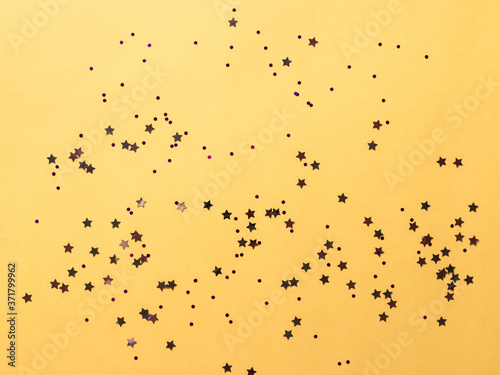 flat lay of shining round, star sparkle on yellow paper background. Decorating for a party. horizontal image