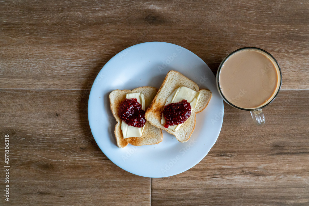 Cup of coffe with milk and two slices of toasted sandwich with Butter and Raspberry Jam. Breakfast with coffee. Top view. Free space for text.