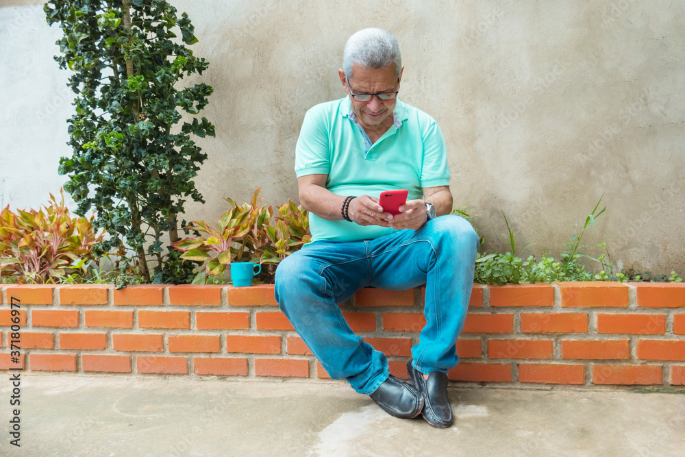 A quiet, mature man with glasses checks his cell phone at home