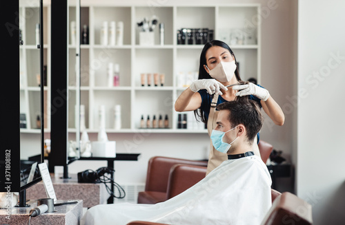 Hairdresser and client in protective medical masks, empty space