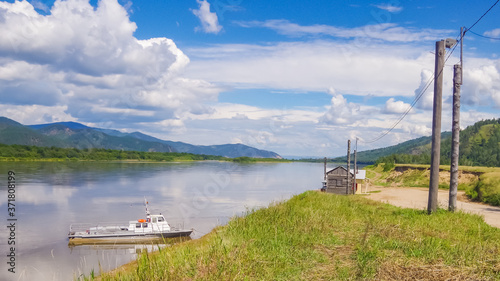Summer landscape on the river in the countryside. Quiet river an old boat is moored to the bank. © Sergey