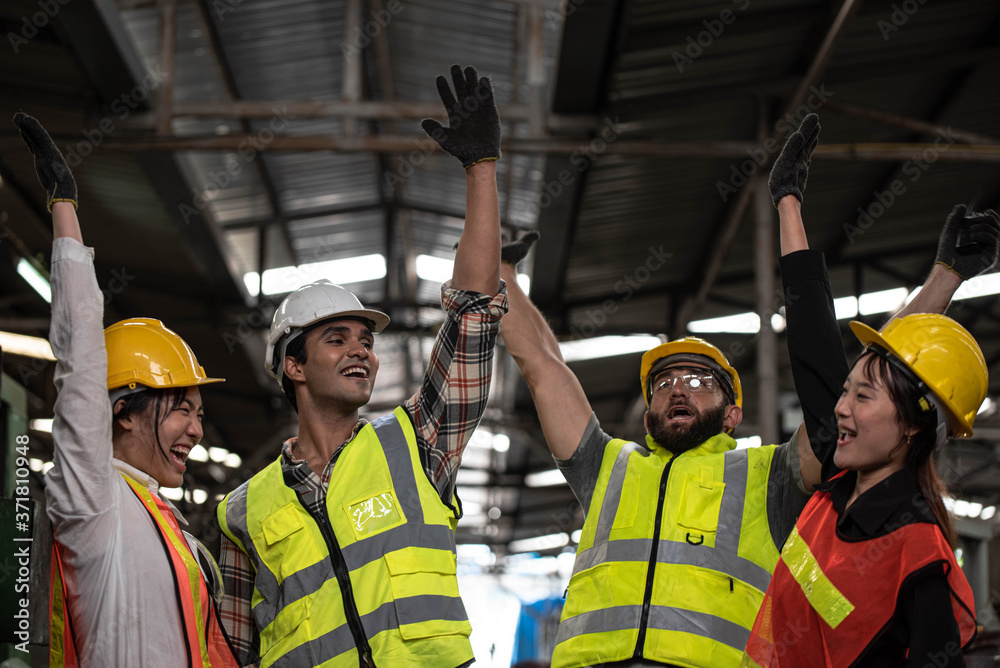 Technicians and Engineer workers  with hardhat or helmet, vest showing hands coordination and raising fist smiling for successful working in workplace of industry Factory/Teamwork co-workers