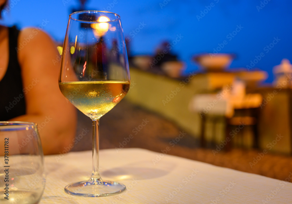 Obraz premium Glass of cold dry white wine served outdoor in cafe at night in Italy
